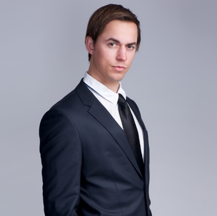 handsome-young-businessman-standing-against-gray-PFGZN4E